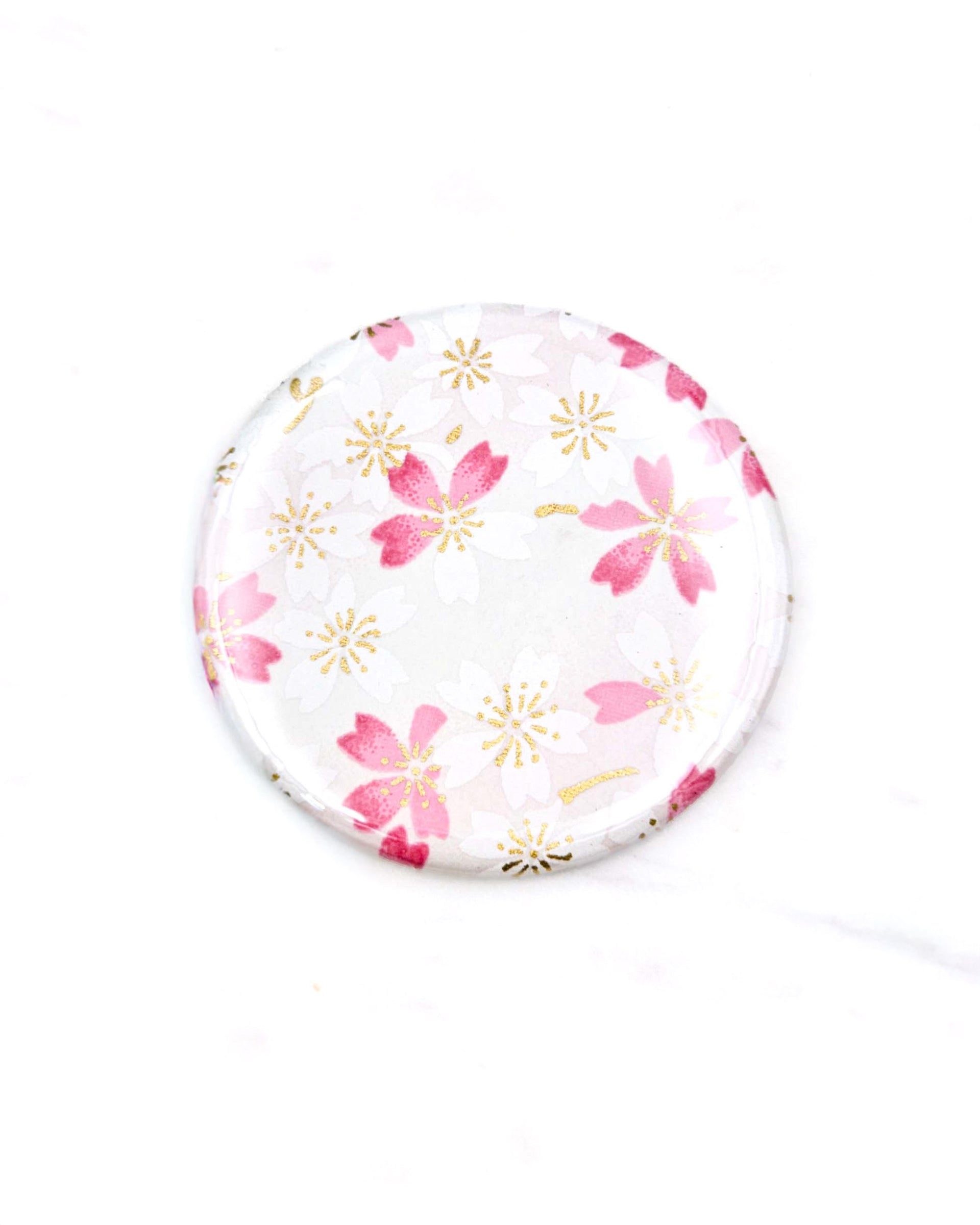 Round pocket mirror featuring pink and white cherry blossoms on a white background with metallic gold accents.