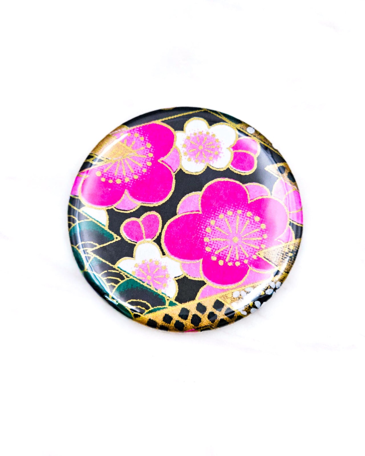 Round pocket mirror featuring pink and white plum blossoms on a black background with metallic gold accents.