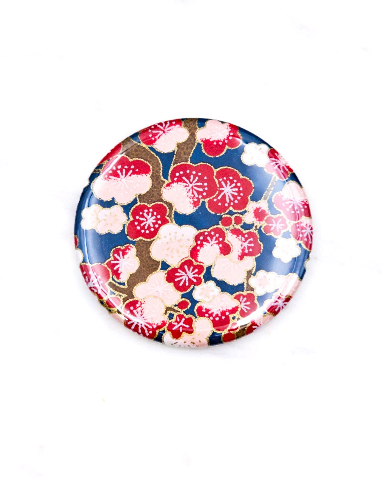 Round pocket mirror featuring a red plum blossom tree on a dark blue background with metallic gold accents.