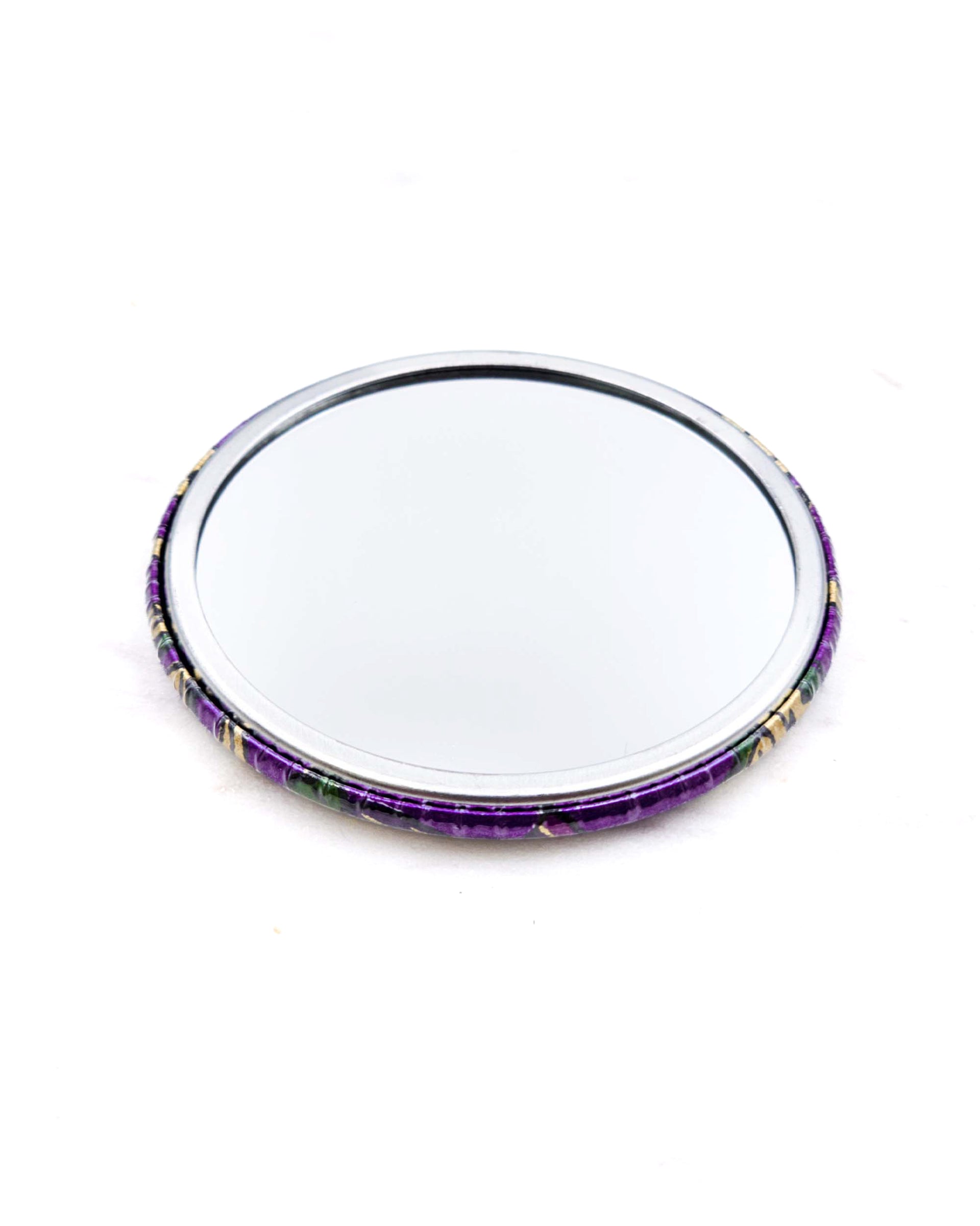 Round pocket mirror featuring green and purple sarasa flowers on a pearlescent purple background with metallic gold accents.