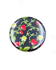 Round pocket mirror featuring strawberries and white flowers on a black background.