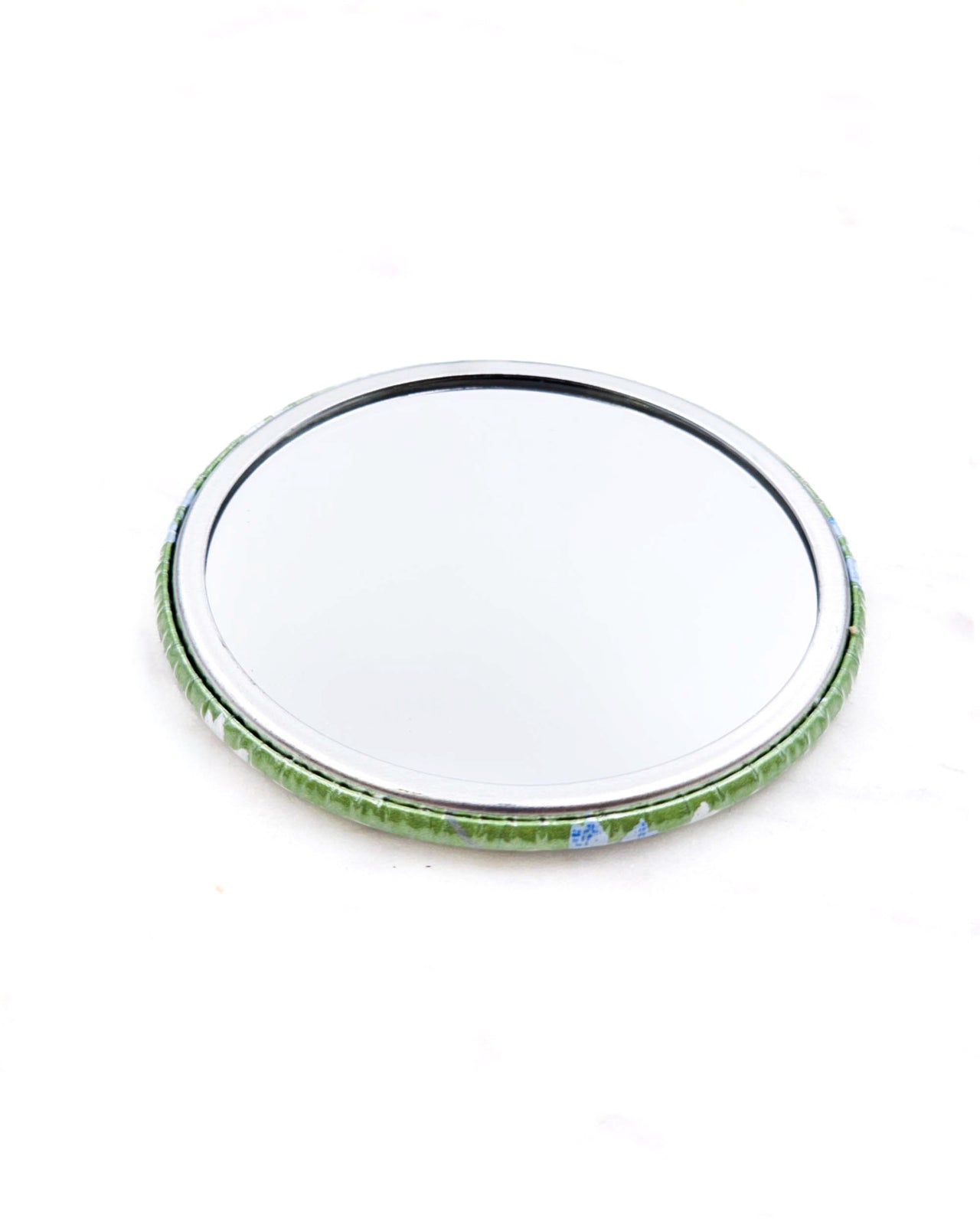 Round pocket mirror featuring small white and blue cherry blossoms on a pearlescent green background.