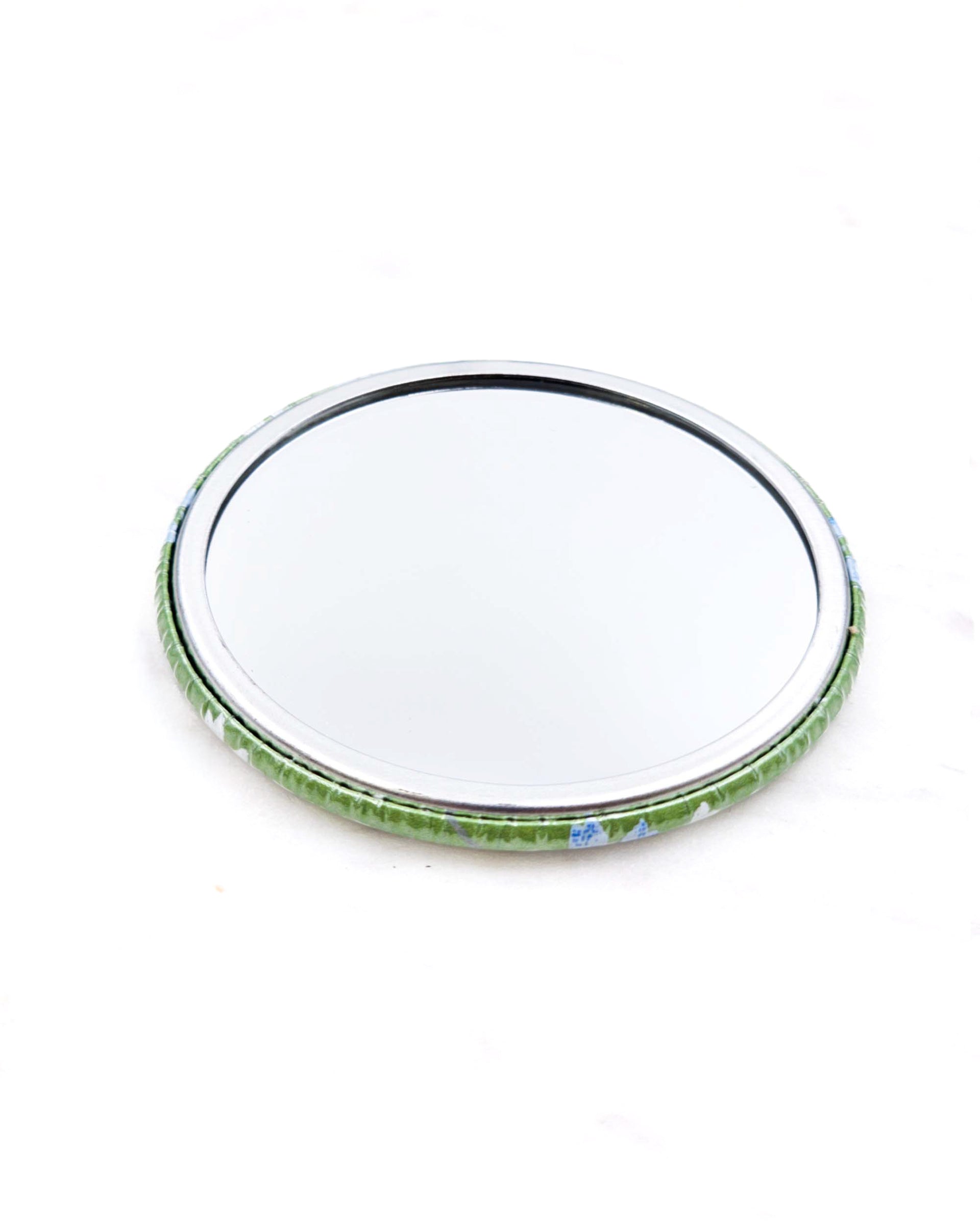 Round pocket mirror featuring small white and blue cherry blossoms on a pearlescent green background.