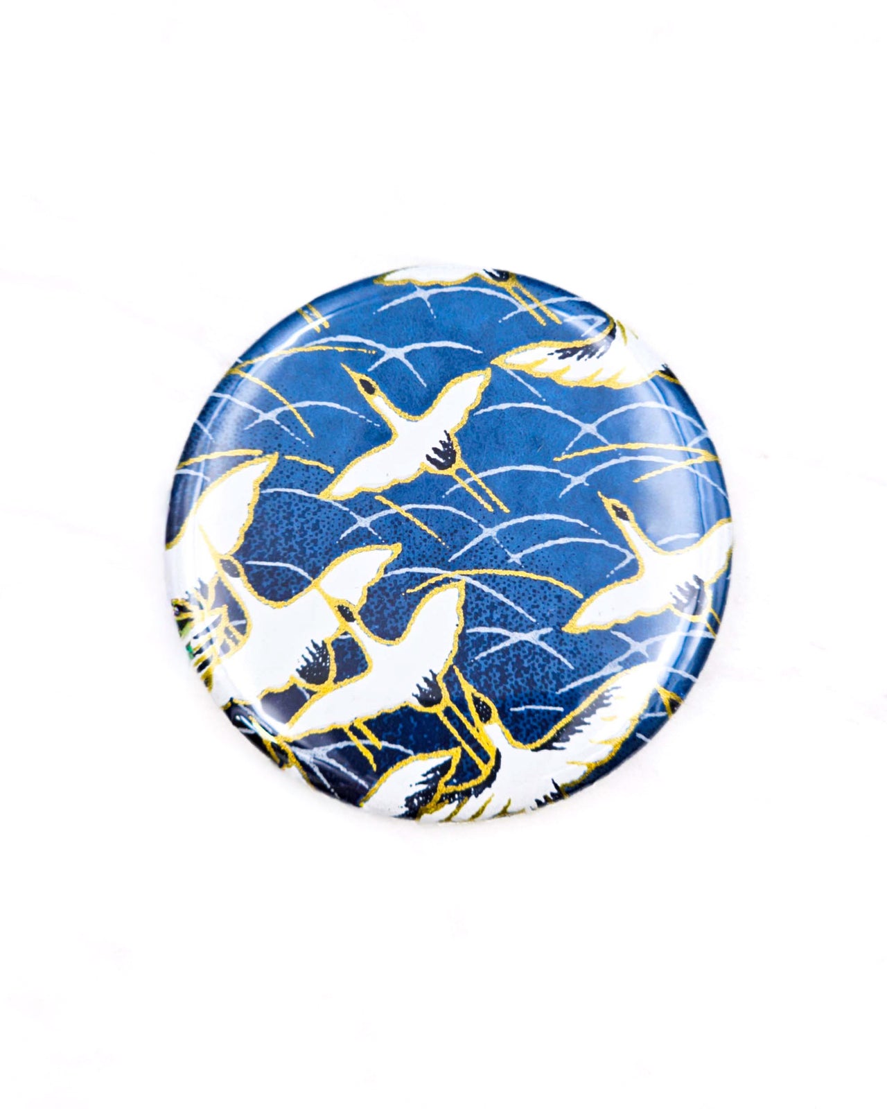 Round pocket mirror featuring white flying cranes on a dark blue background with metallic gold accents.