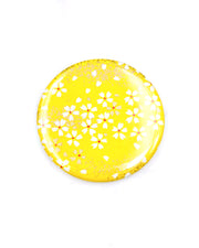Round pocket mirror featuring small white and gold cherry blossoms on a yellow background with metallic gold accents.
