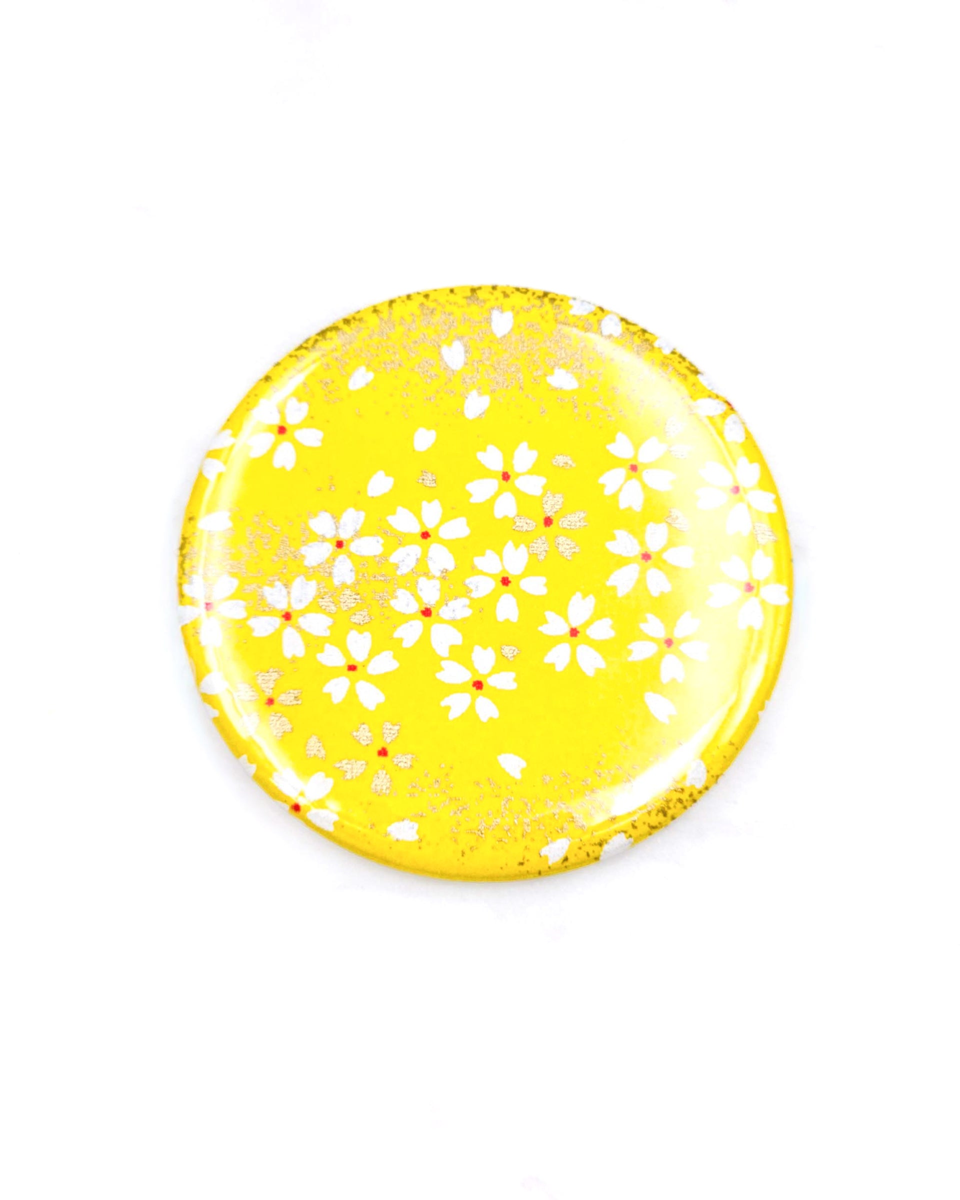 Round pocket mirror featuring small white and gold cherry blossoms on a yellow background with metallic gold accents.