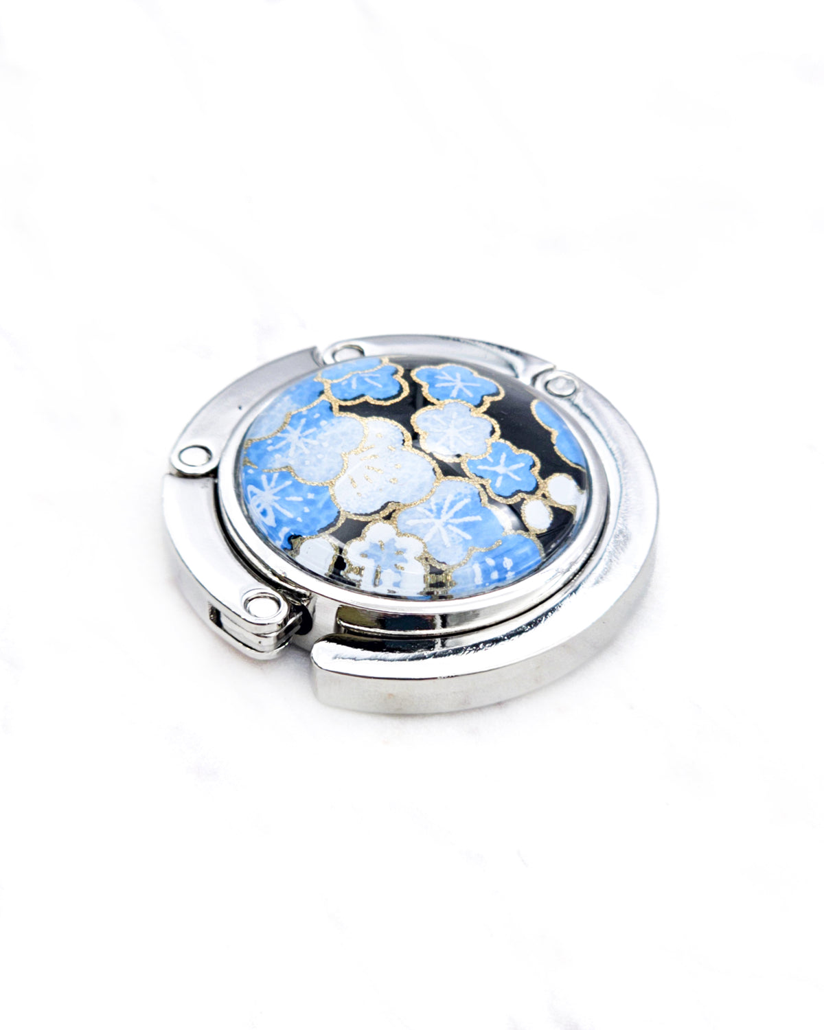 Round silver metal tabletop bag hanger featuring blue and white plum blossoms on a black background with metallic gold details.