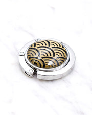 Silver metal table-top bag hanger featuring a traditional gold and black seigaiha (wave crests) design.