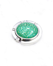 Round silver metal tabletop bag hanger featuring a metallic gold traditional Japanese sayagata design on a green background.