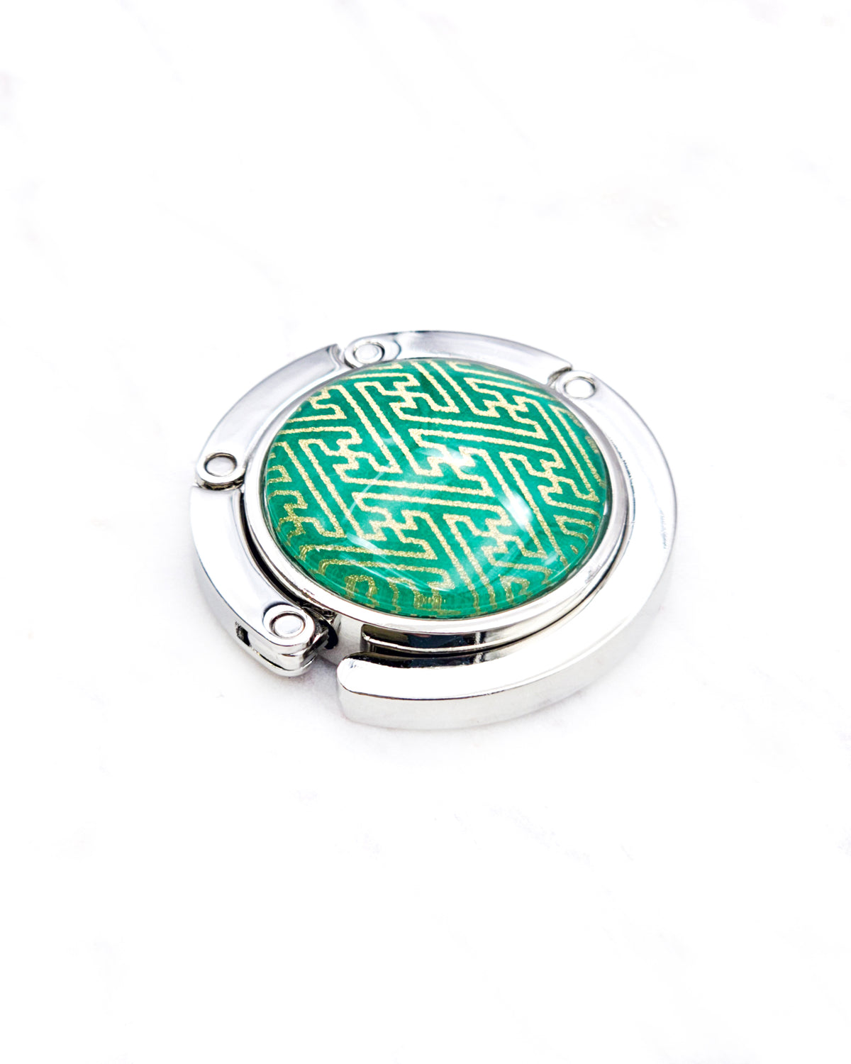 Round silver metal tabletop bag hanger featuring a metallic gold traditional Japanese sayagata design on a green background.