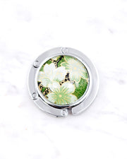 Silver metal table-top bag hanger featuring green cherry blossoms on a green background with metallic gold accents.