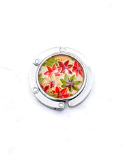 Round silver metal table-top bag hanger featuring small orange, green, and red Japanese maple leaves with metallic gold details.