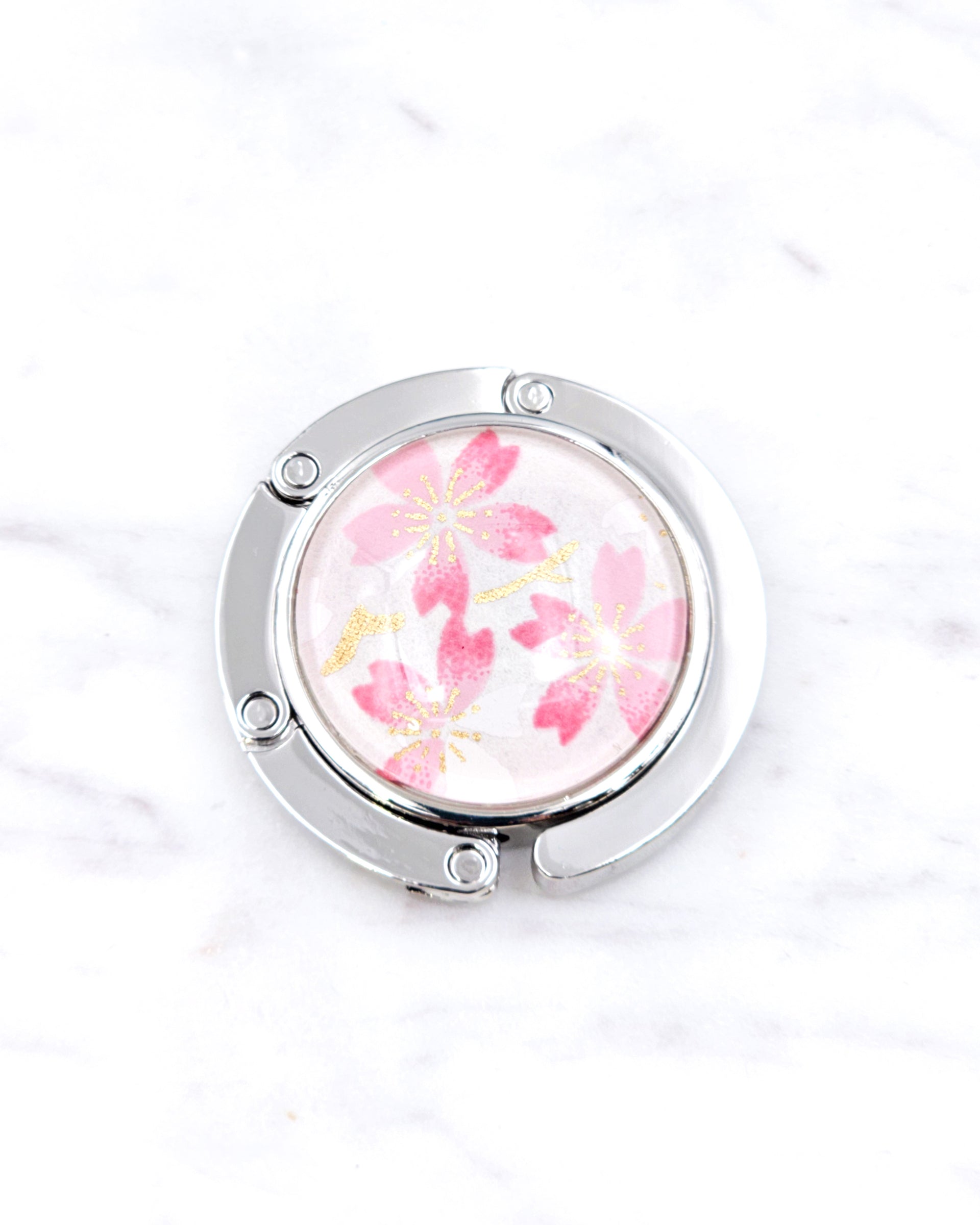 Silver metal table-top bag hanger featuring pink cherry blossoms on a white background with metallic gold accents.