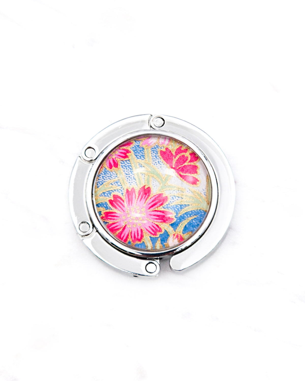 Round silver metal tabletop bag hanger featuring pink flowers with green stems on a blue and white background with metallic gold details.