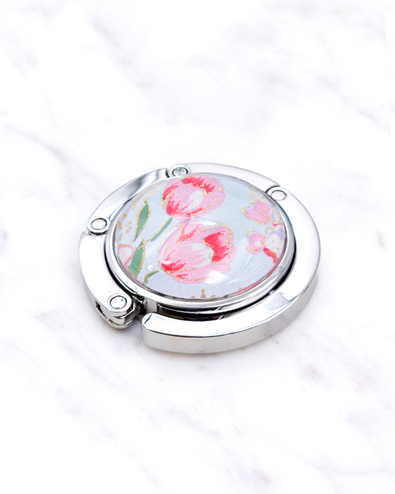 Silver metal table-top bag hanger featuring pink tulips on a light blue background with metallic gold accents.