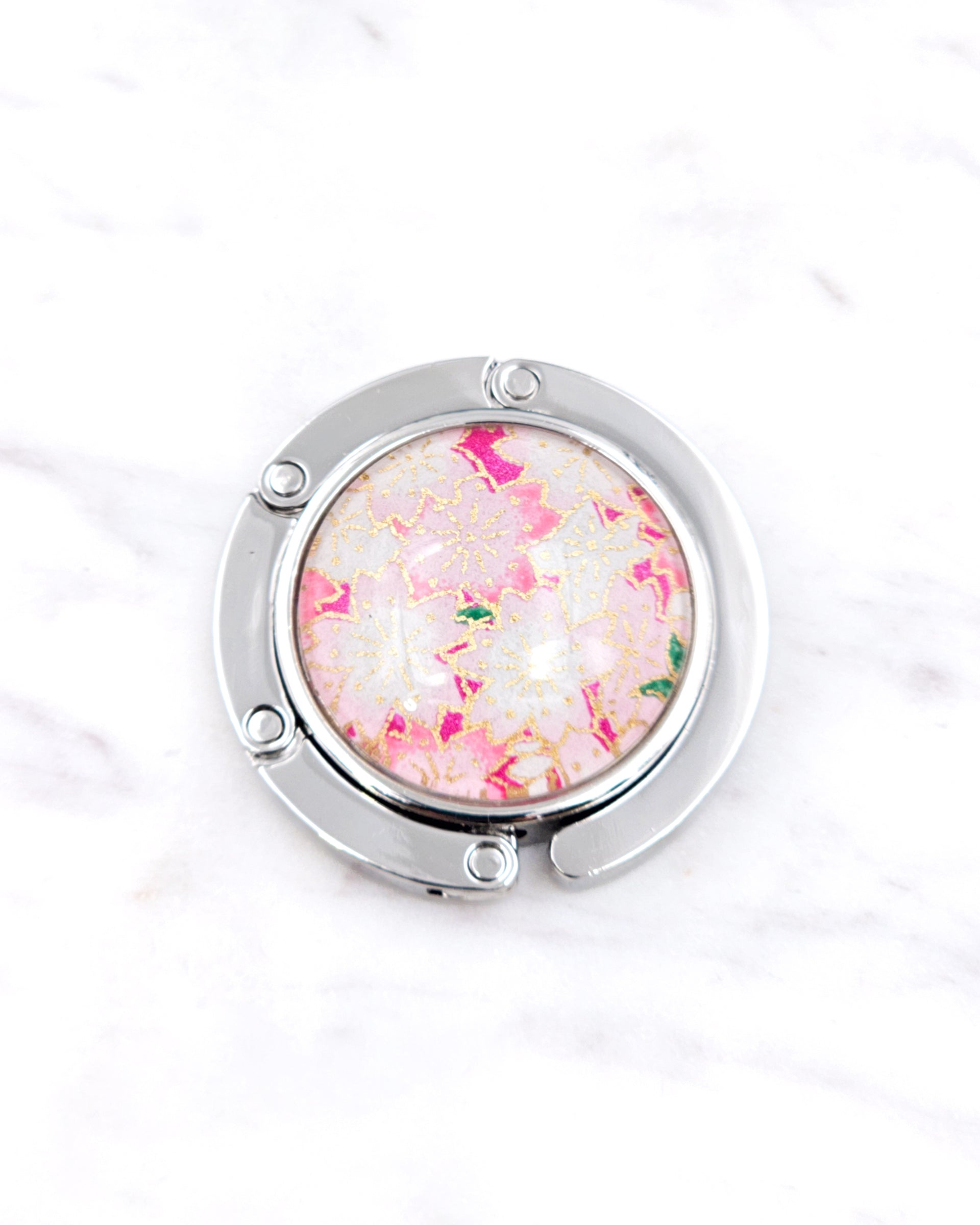 Silver metal table-top bag hanger featuring pink and white cherry blossoms on a pink background with metallic gold accents.