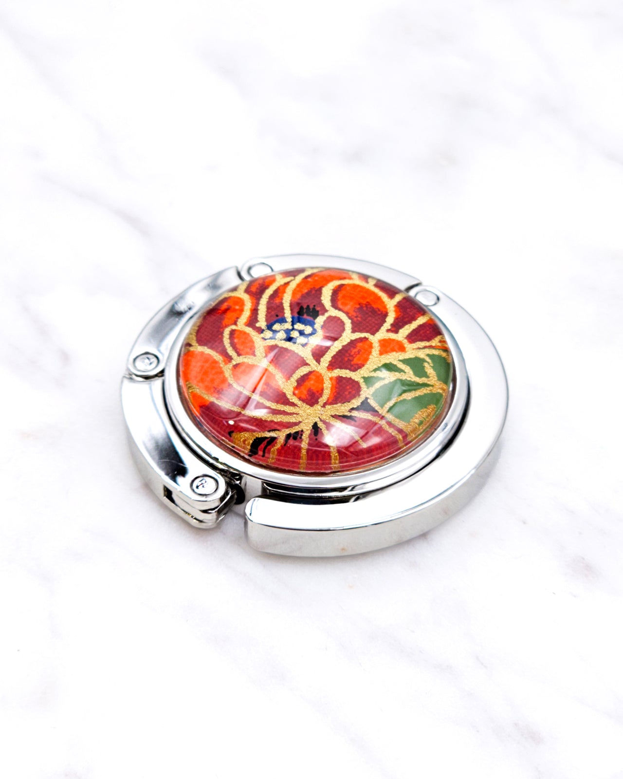 Silver metal table-top bag hanger featuring a red chrysanthemum flower with metallic gold accents.