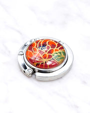 Silver metal table-top bag hanger featuring a red chrysanthemum flower with metallic gold accents.