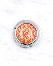 Silver metal table-top bag hanger featuring a traditional red and gold kikkou (tortoiseshell) design.