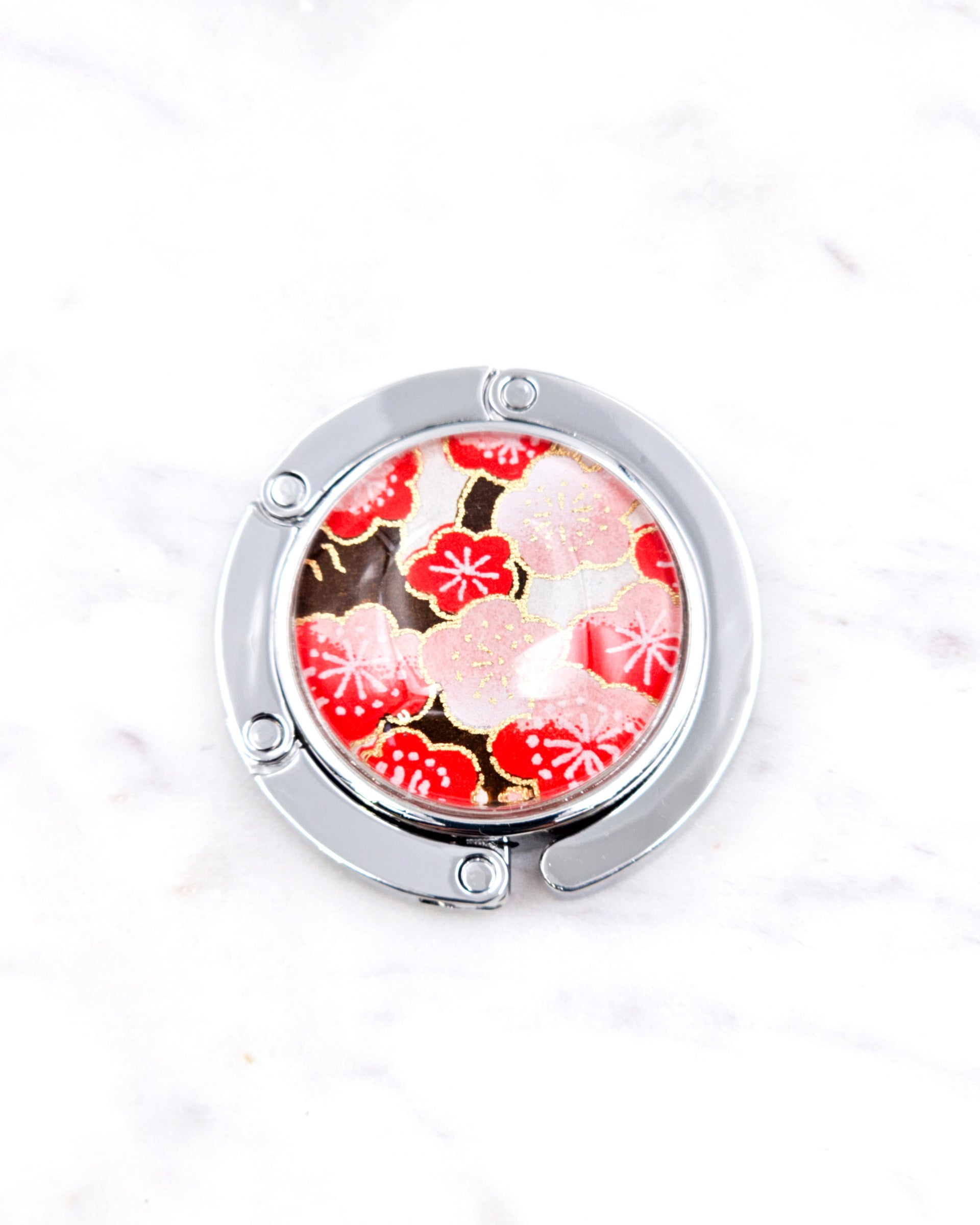 Silver metal table-top bag hanger featuring red plum blossoms on a white background with metallic gold accents.