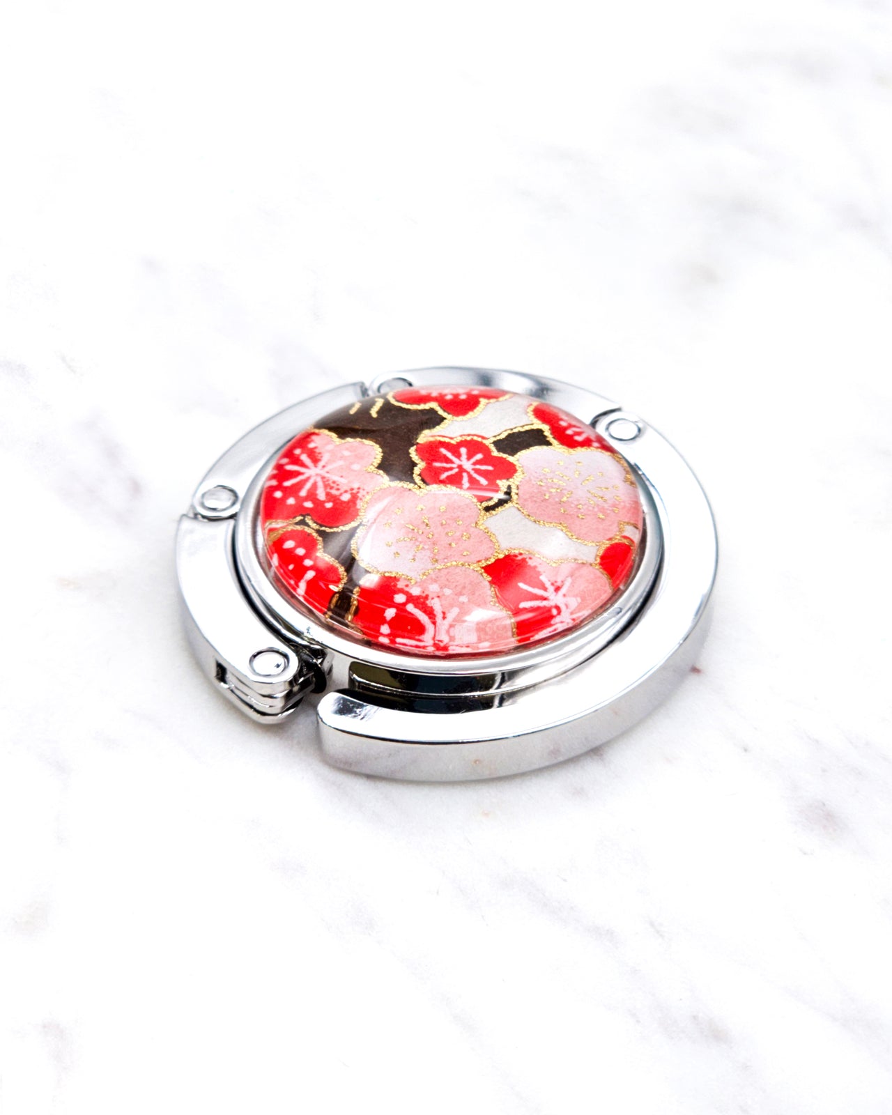 Silver metal table-top bag hanger featuring red plum blossoms on a white background with metallic gold accents.