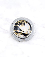 Silver metal table-top bag hanger featuring a white crane on a black background design with metallic gold accents.