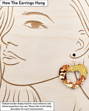 X-Large wooden hollow heart shaped earrings featuring white plum blossom branches on a maroon red and brown background with metallic gold details, displayed on a stylized wooden head to demonstrate how the earring hangs when worn. Display is not to scale.