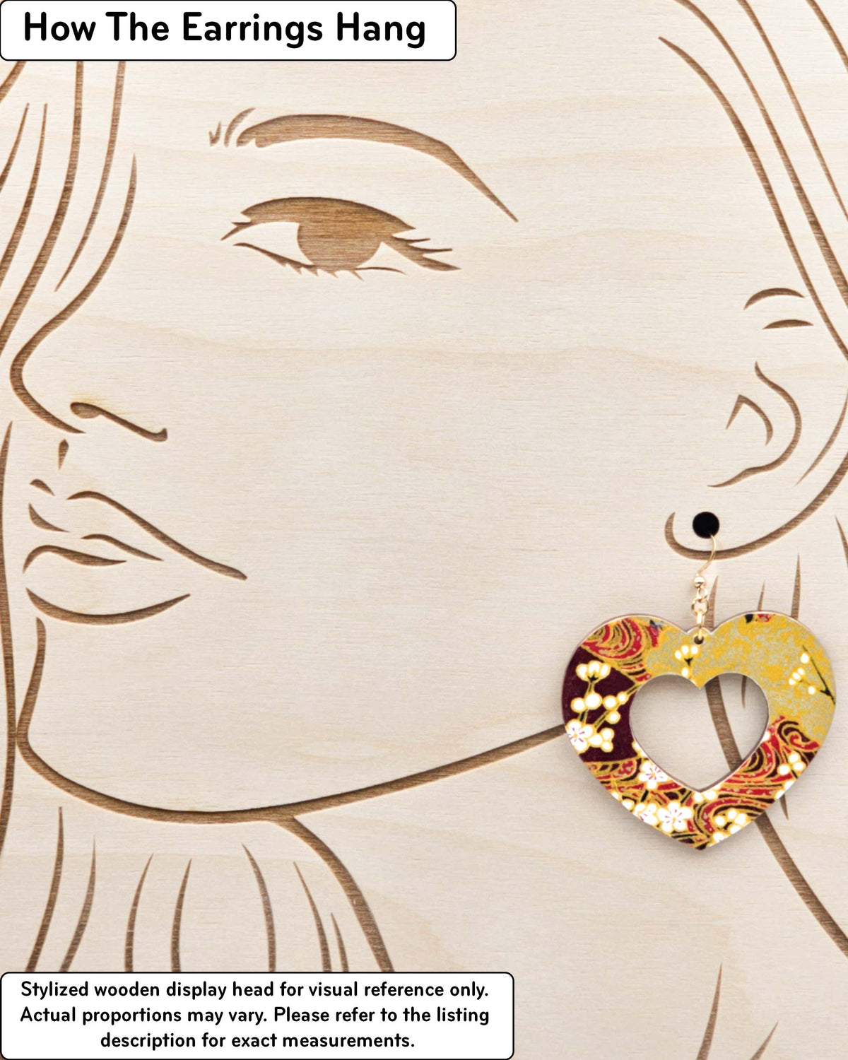 X-Large wooden hollow heart shaped earrings featuring white plum blossom branches on a maroon red and brown background with metallic gold details, displayed on a stylized wooden head to demonstrate how the earring hangs when worn. Display is not to scale.
