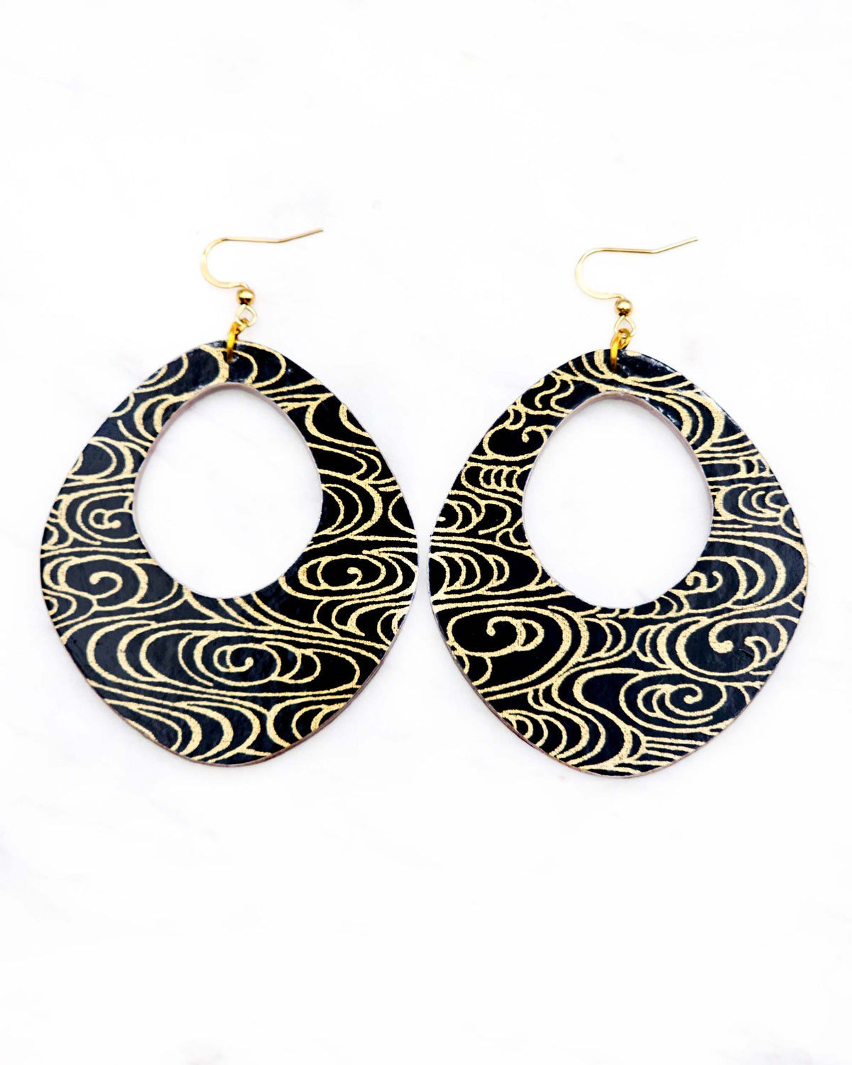 X-Large wooden abstract hoop shaped earrings featuring metallic gold water ripples on a black background.