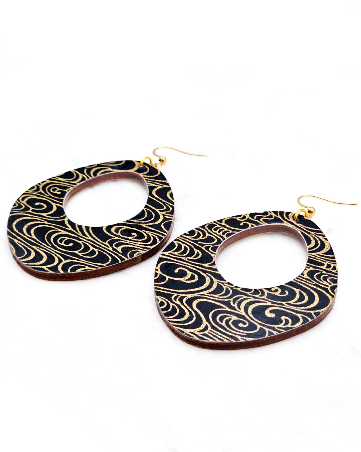 X-Large wooden abstract hoop shaped earrings featuring metallic gold water ripples on a black background.