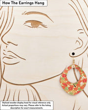 X-Large wooden abstract hoop shaped earrings featuring small red, green, and white momiji (maple leaves) on a gold background with metallic gold details, displayed on a stylized wooden head to demonstrate how the earring hangs when worn. Display is not to scale.