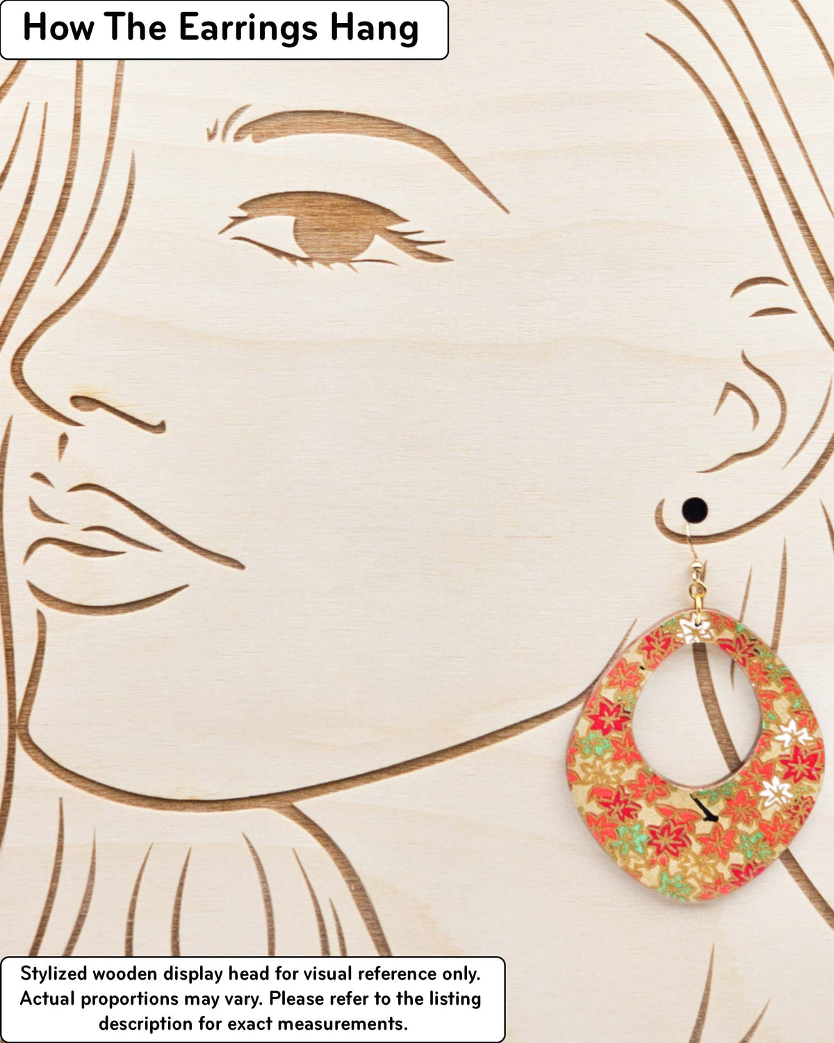 X-Large wooden abstract hoop shaped earrings featuring small red, green, and white momiji (maple leaves) on a gold background with metallic gold details, displayed on a stylized wooden head to demonstrate how the earring hangs when worn. Display is not to scale.