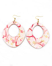 X-Large wooden abstract hoop shaped earrings featuring small white and gold cherry blossoms and large pink cherry blossom outlines on a light pink background with metallic gold details.