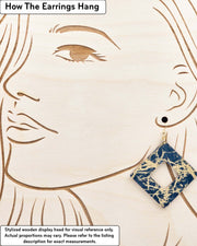 X-Large wooden hollow square diamond shaped earrings featuring metallic gold fibers in the style of traditional unryu paper on a dark blue background, displayed on a stylized wooden head to demonstrate how the earring hangs when worn. Display is not to scale.