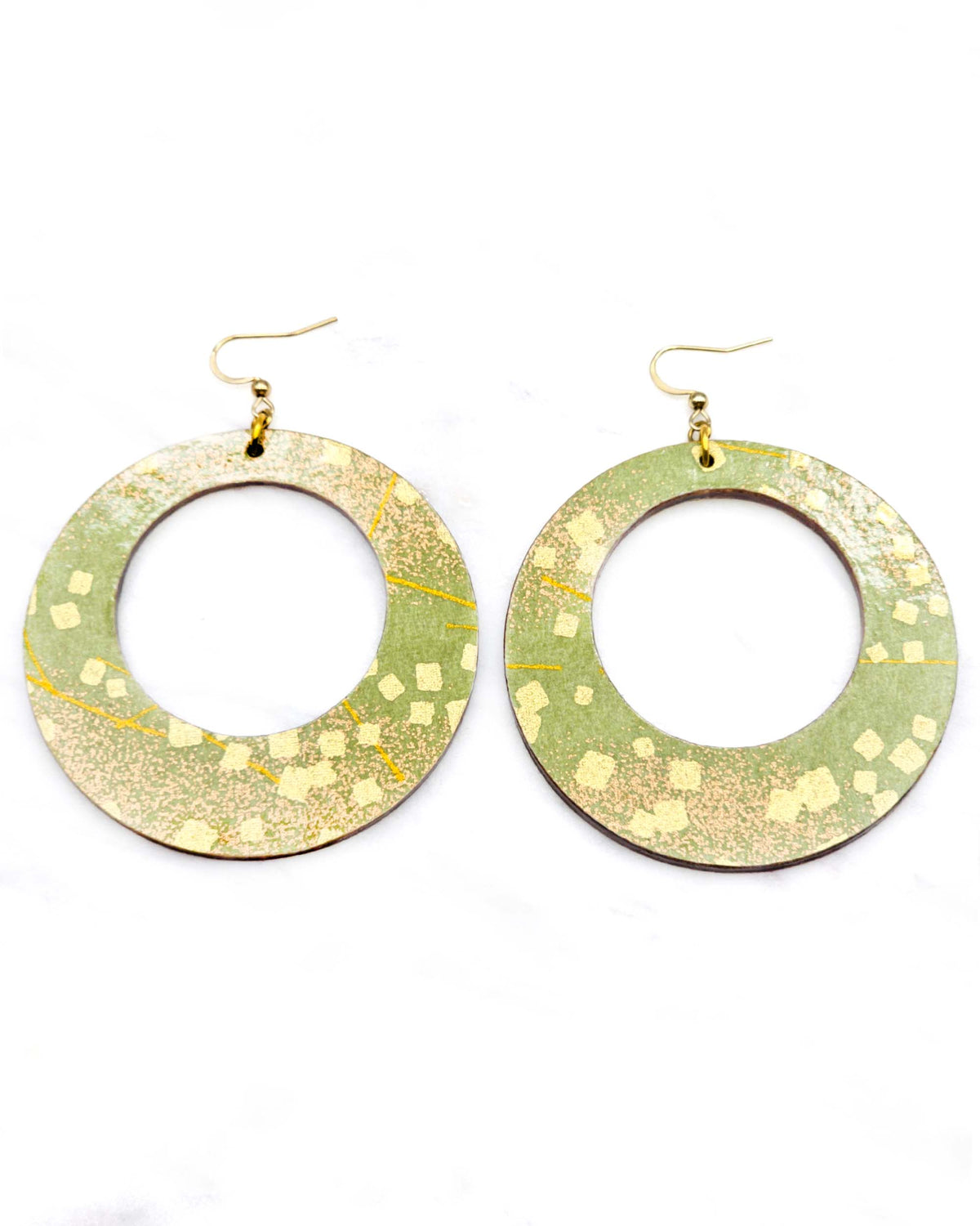 X-Large wooden round hoop shaped earrings featuring scattered metallic gold geometric shapes and fine gold lines on a green background.