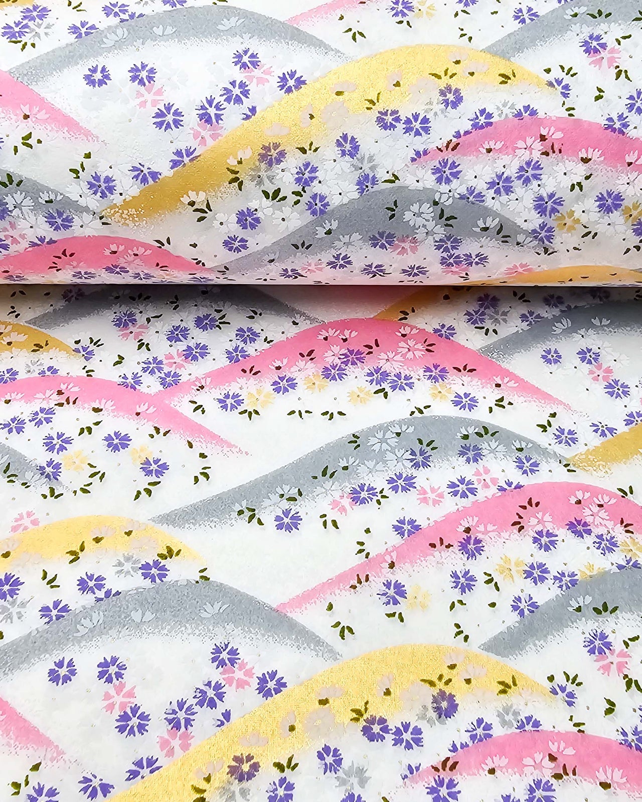 Japanese chiyogami paper featuring pink, gray, and gold hills with purple, pink, and white cherry blossoms on a white background with metallic gold details