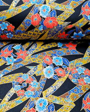 Japanese chiyogami paper featuring red and blue flowers intertwined in yellow and blue ribbons with a shippo floral pattern on a black background with metallic gold details.