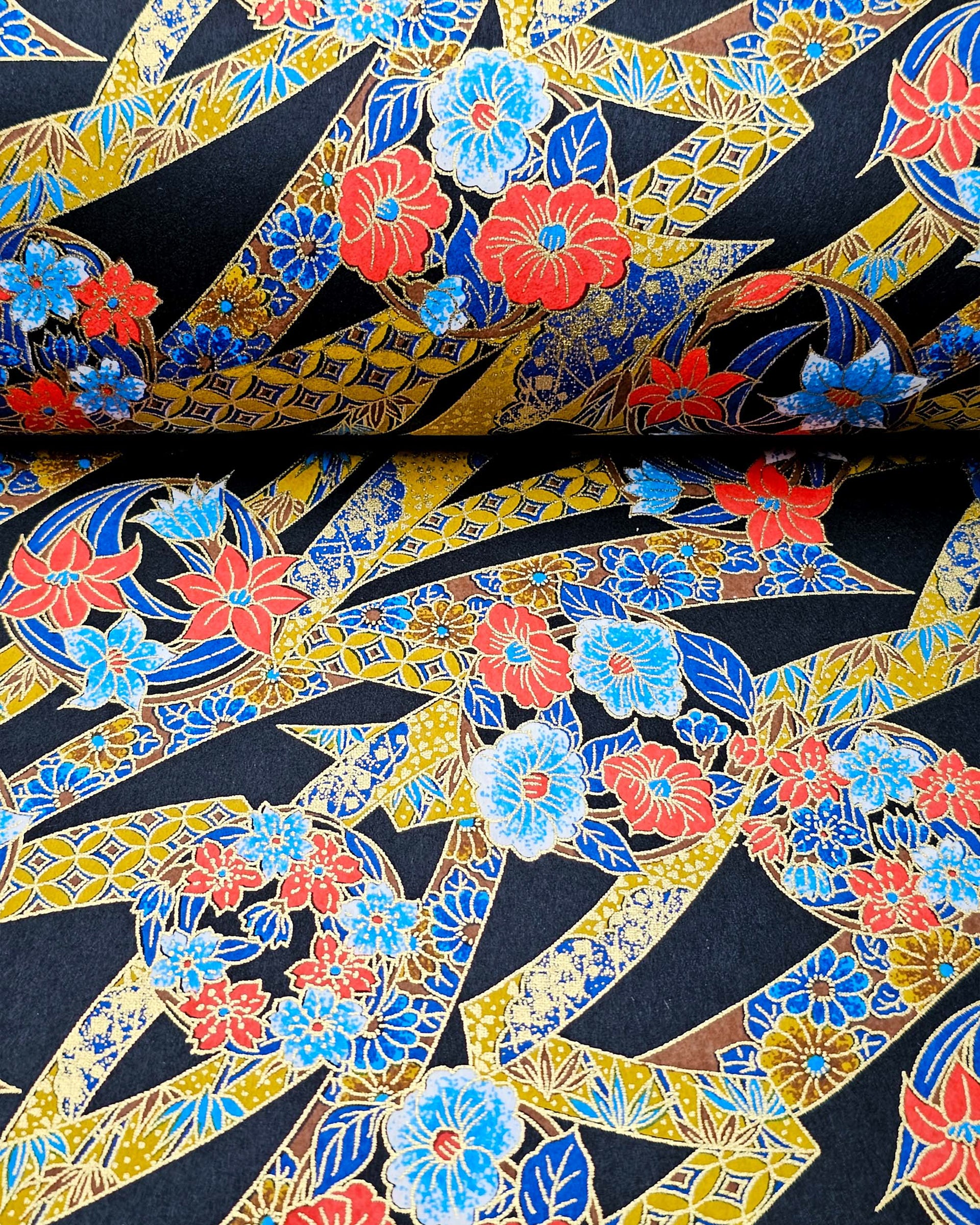 Japanese chiyogami paper featuring red and blue flowers intertwined in yellow and blue ribbons with a shippo floral pattern on a black background with metallic gold details.