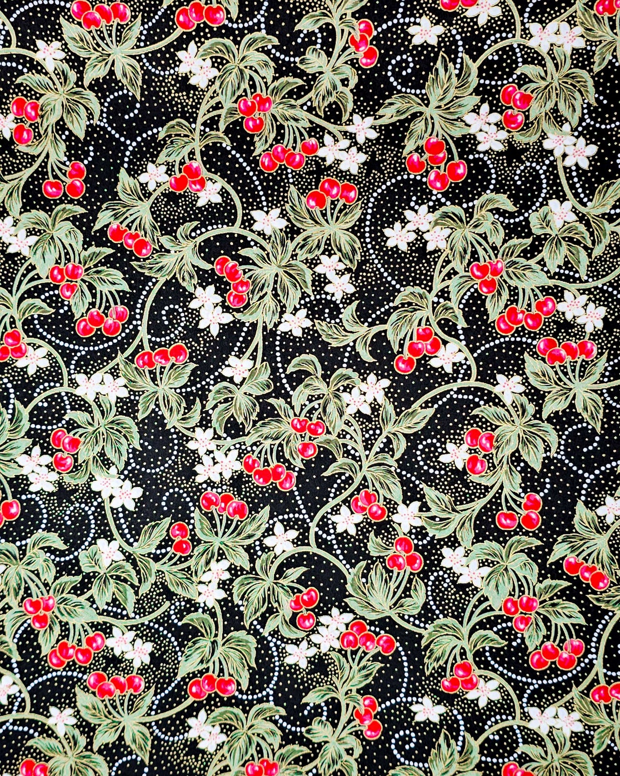 Japanese chiyogami paper featuring red cherries with white flowers and green leaves on a black background with metallic gold details.