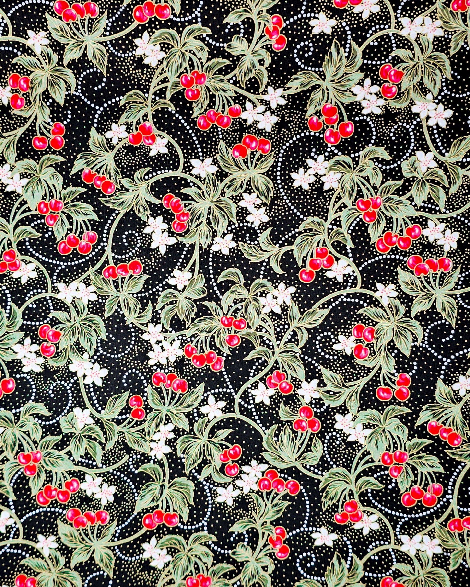 Japanese chiyogami paper featuring red cherries with white flowers and green leaves on a black background with metallic gold details.