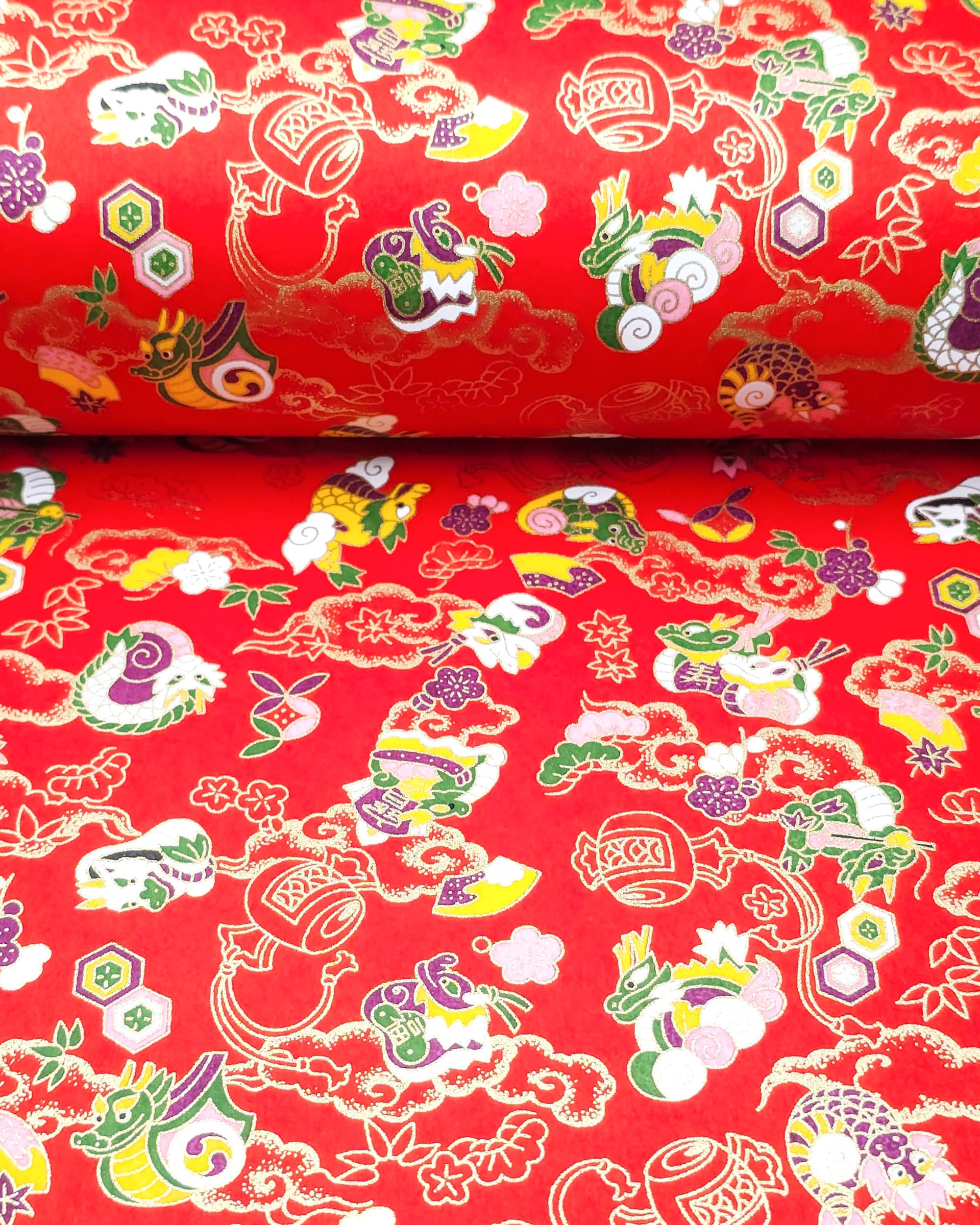 Japanese chiyogami paper featuring assorted white, purple, green, and yellow dragons on a red background with metallic gold details.