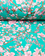 Japanese chiyogami paper featuring pink and white detailed plum blossoms with brown branches and green leaves on a turquoise background with metallic gold details.