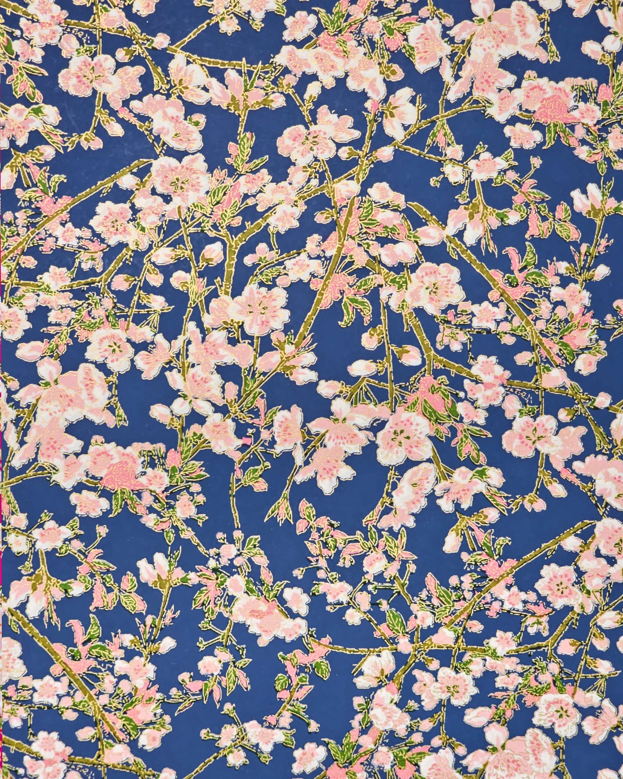 Japanese chiyogami paper featuring pink and white detailed plum blossoms with brown branches and green leaves on a dark blue background with metallic gold details.