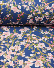 Japanese chiyogami paper featuring pink and white detailed plum blossoms with brown branches and green leaves on a dark blue background with metallic gold details.