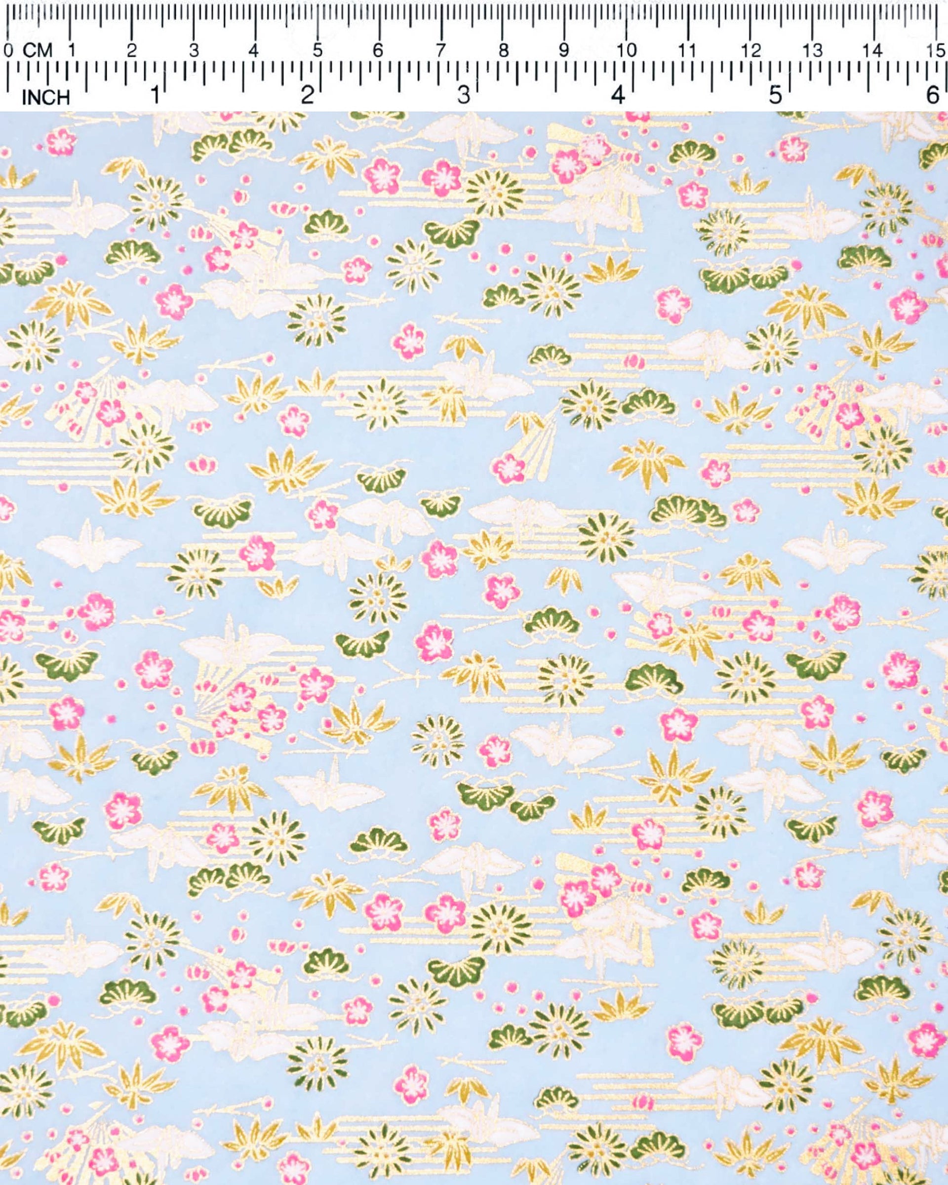 Japanese chiyogami paper featuring white origami cranes with green plants and pink plum blossoms on a light blue background with metallic gold details.