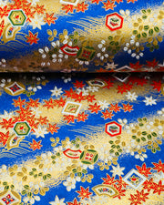 Japanese chiyogami paper featuring red and white maple leaves and traditional motifs on a blue and gold background with metallic gold details.