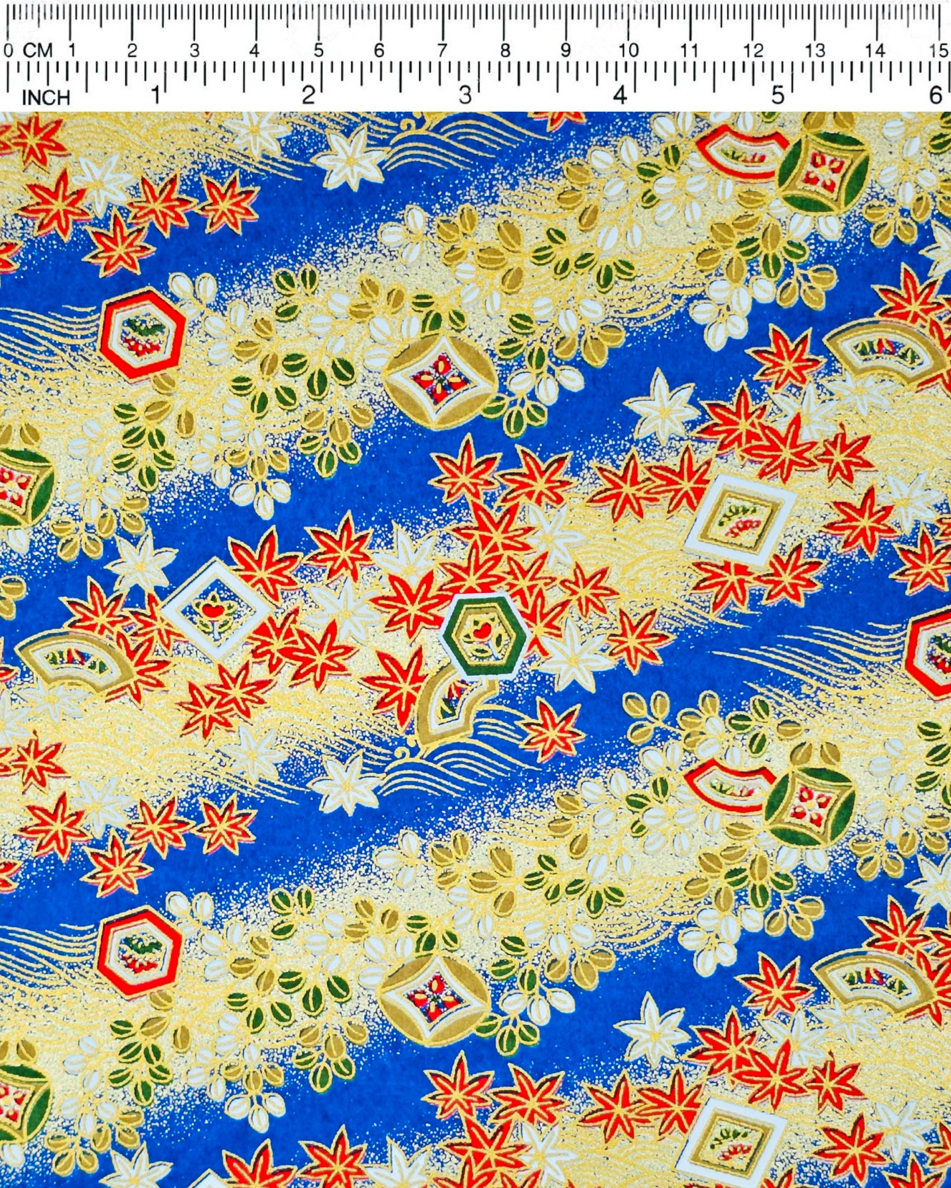 Japanese chiyogami paper featuring red and white maple leaves and traditional motifs on a blue and gold background with metallic gold details.