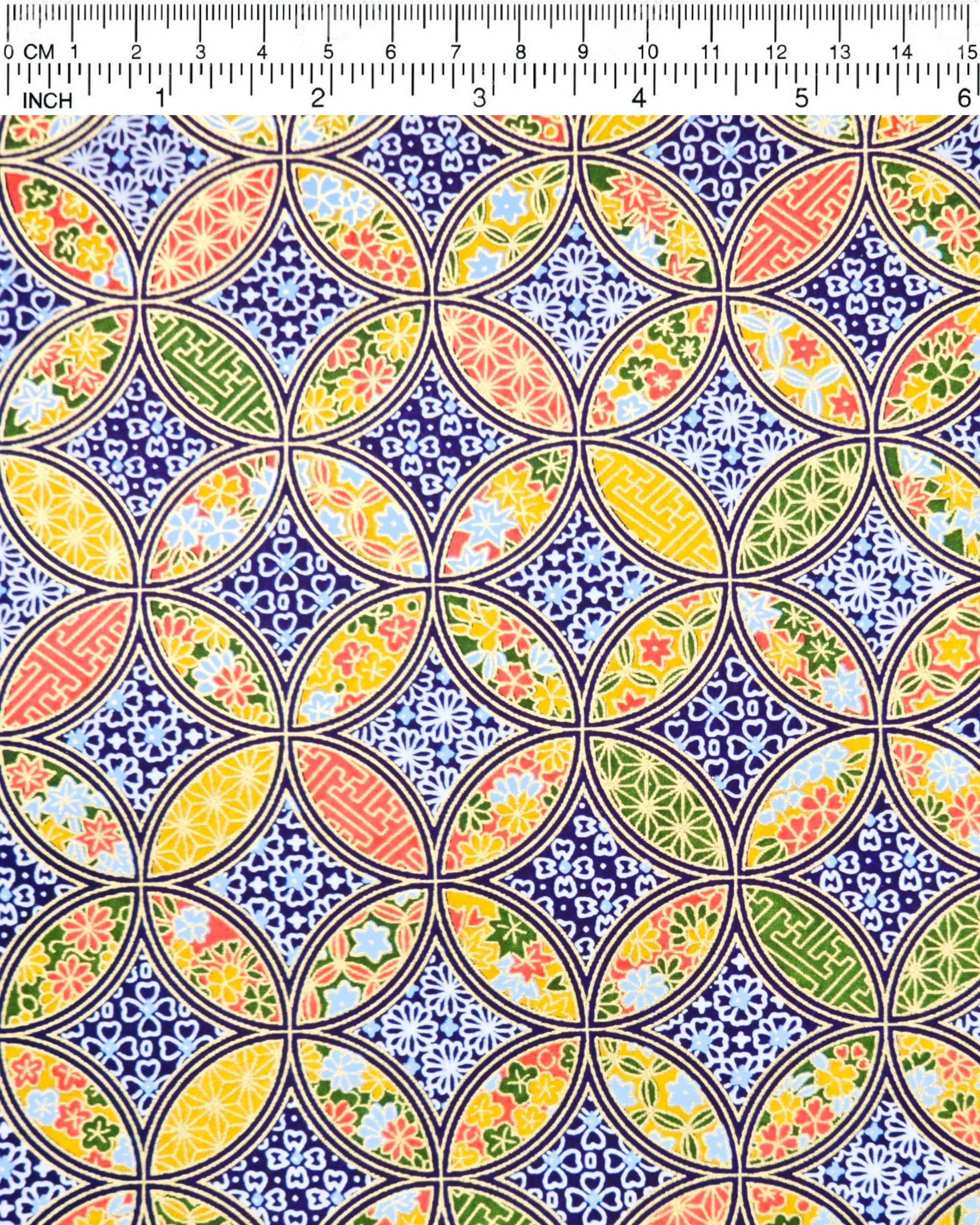 Japanese chiyogami paper featuring an orange, yellow, and green shippo design filled with assorted floral and geometric designs on a dark blue background with metallic gold details. The centers of the shippos features assorted white floral outlines.