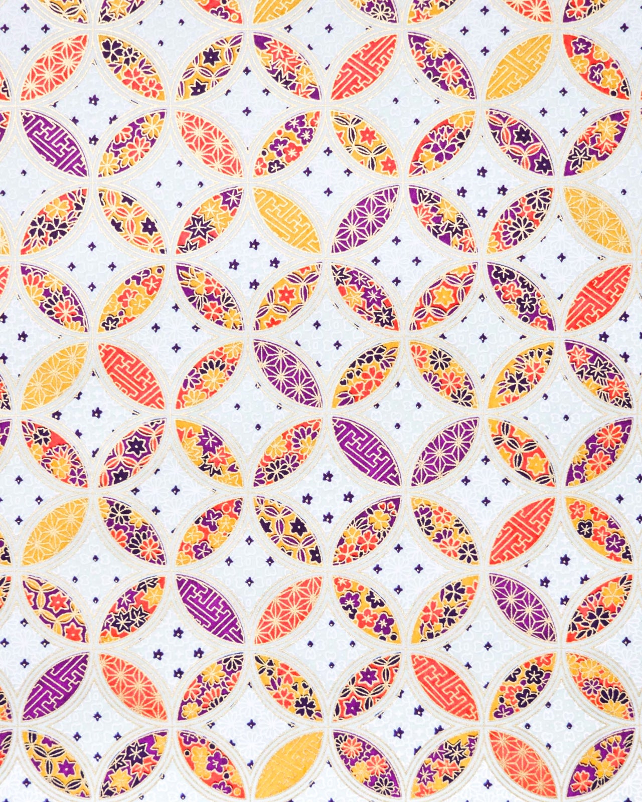 Japanese chiyogami paper featuring an orange, yellow, and purple shippo design filled with assorted floral and geometric designs on a light blue background with metallic gold details. The centers of the shippos features assorted white floral outlines.