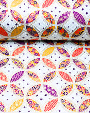 Japanese chiyogami paper featuring an orange, yellow, and purple shippo design filled with assorted floral and geometric designs on a light blue background with metallic gold details. The centers of the shippos features assorted white floral outlines.